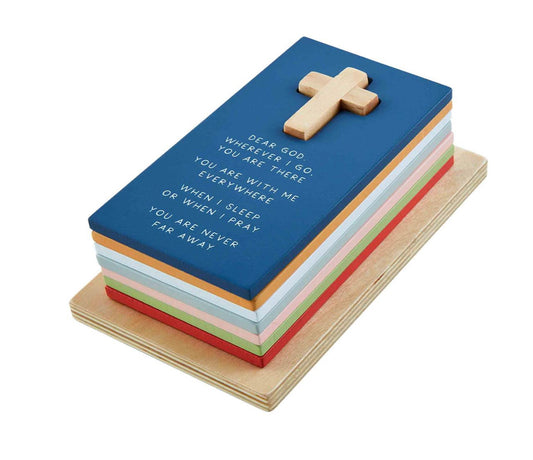 A rectangular Prayer Puzzle Stacker cake designed like a book with a blue cover and a gold cross on top. The cake features an inscription in icing starting with "Dear God, where are you…" on a white and multicolored base.