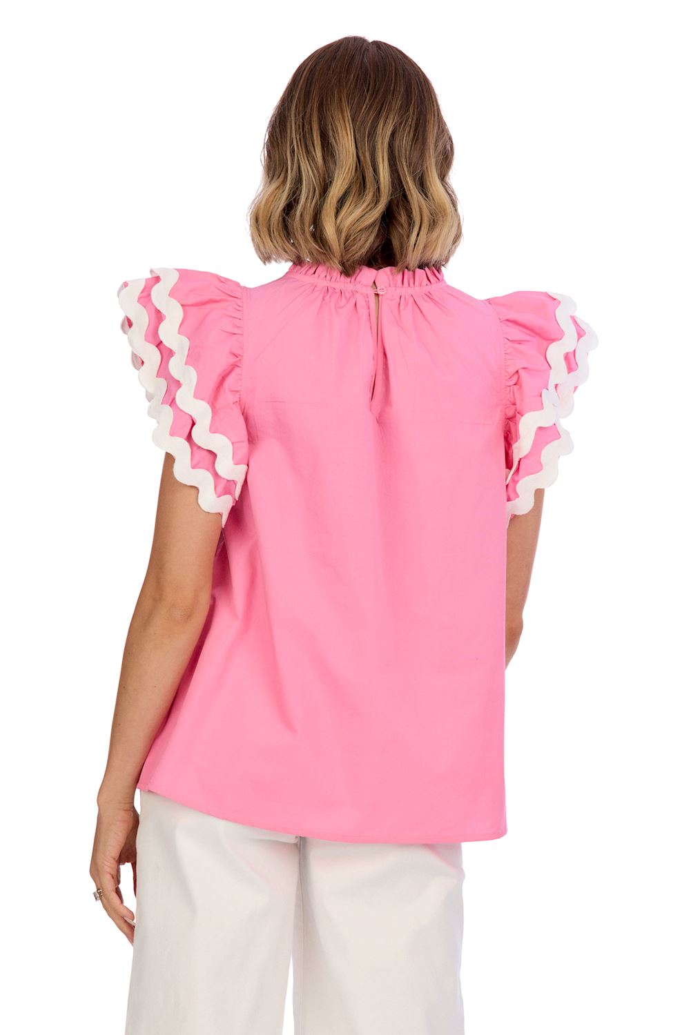 The Angie Ric Rac Top in pink features flutter sleeves with ruffled white edges and a keyhole neckline at the back. Available sizes: XS, S, M, L.