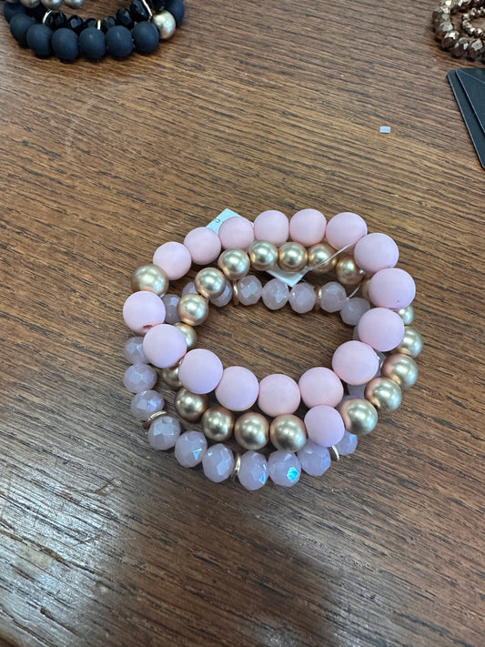 This product is a stack of three Clay Ball Bracelets. The beads used are 12MM in size and come in colors of pink and golden. These bracelets are prearranged in a graduating circular shape, with the largest bracelet positioned at the bottom.