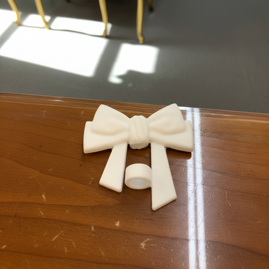 Large double ribbon bow straw cover in white plastic with attached ring, available in multiple sizes.