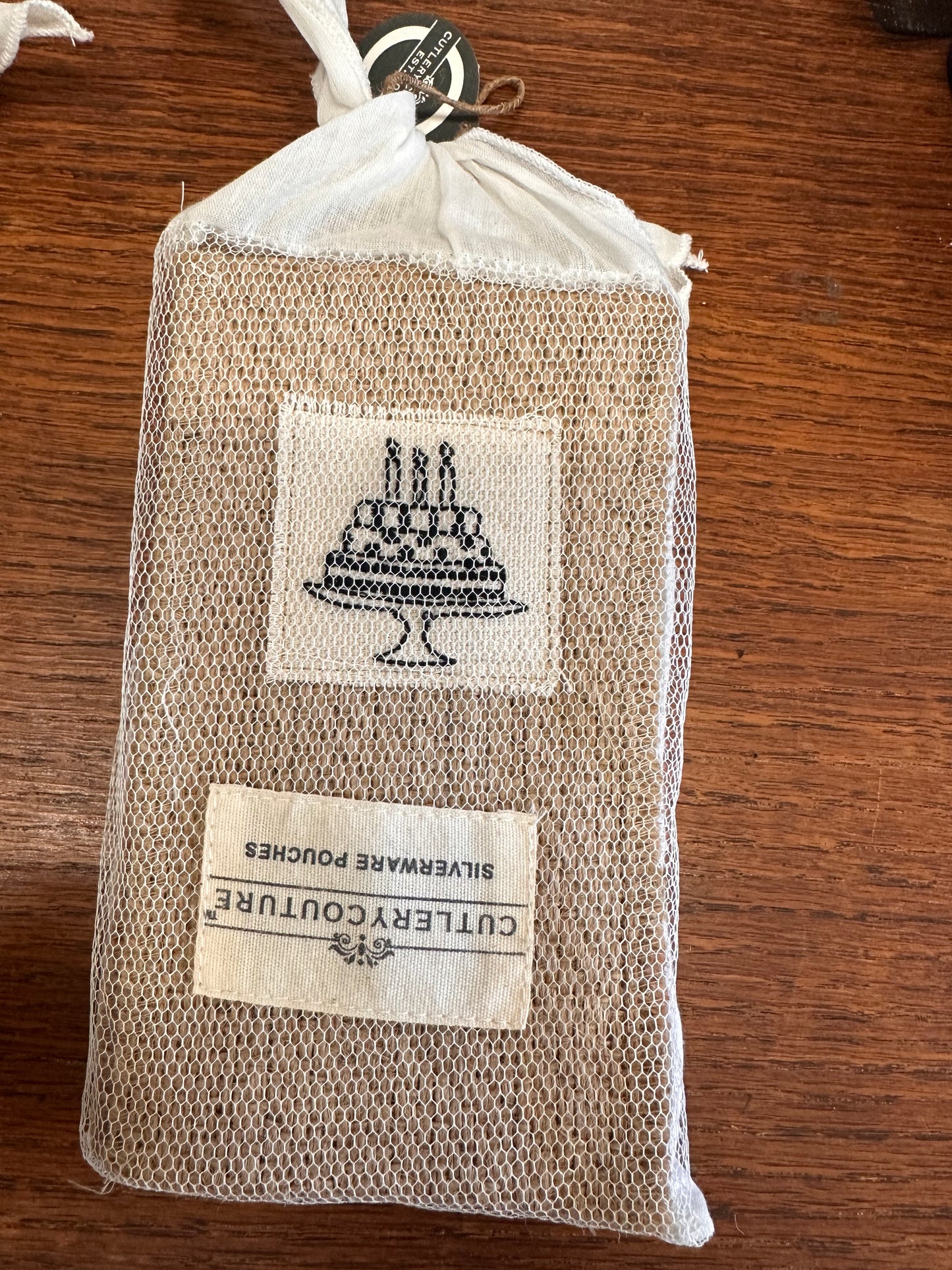 Mesh drawstring pouch with printed cake and candles, labeled "Cutlery Couture Silverware Pouches." Available in multiple sizes.