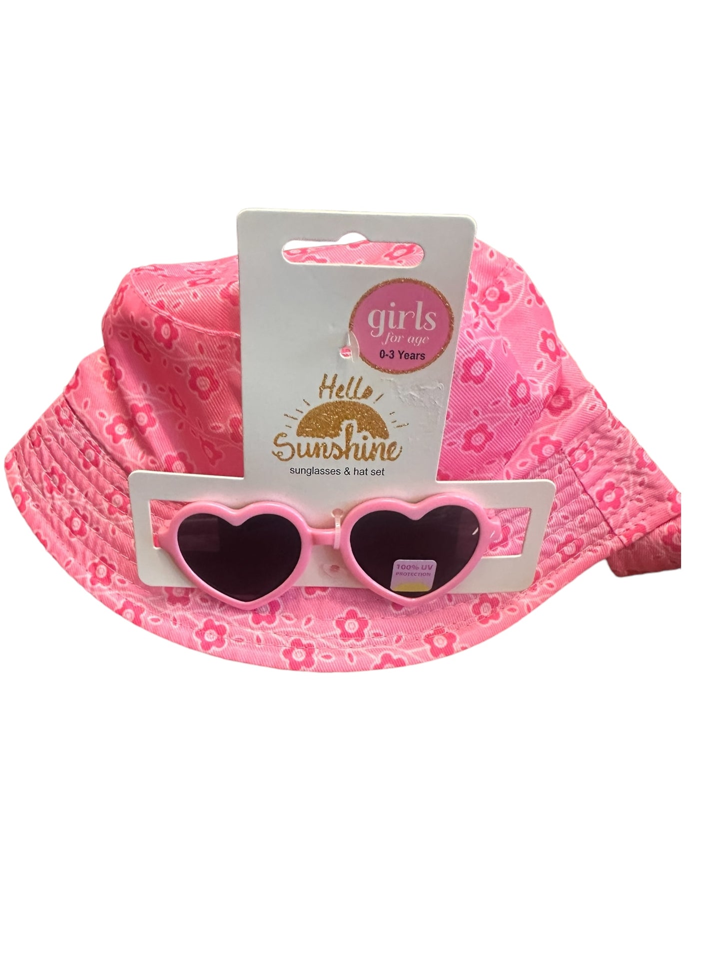 Pink sun hat with floral pattern and heart-shaped sunglasses. UV400 protection. Sizes: 0-3 years. Labeled "Hello Sunshine." Product: Kids Sunnies & Hat Sets.
