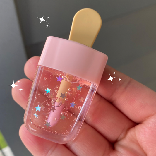 This lip gloss is clear and changes according to the temperature of your lips changing to a soft pink it has holographic stars and inside of the gloss. It measures proximately 2“ x 1“ the top part of the popsicle is clear and the bottom is pale pink with a beigestick