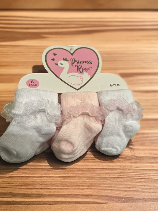 A pack of infant socks labeled "princess rose" displayed on a wooden surface. the set includes three pairs: two in white and one in pink, each adorned with delicate lace trim.