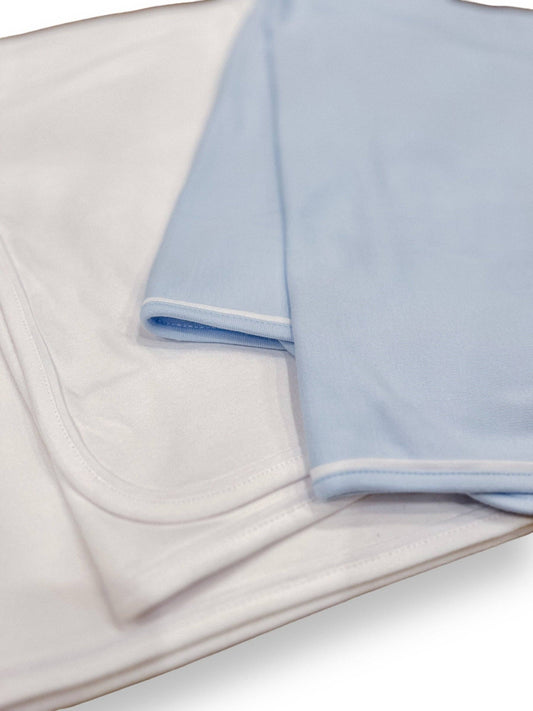 Close-up of a white baby blanket with piping neatly folded on a plain background, highlighting the smooth texture and clean design of the double layered cotton fabric.