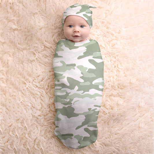 Baby in camo cocoon with matching hat on a white faux fur rug.