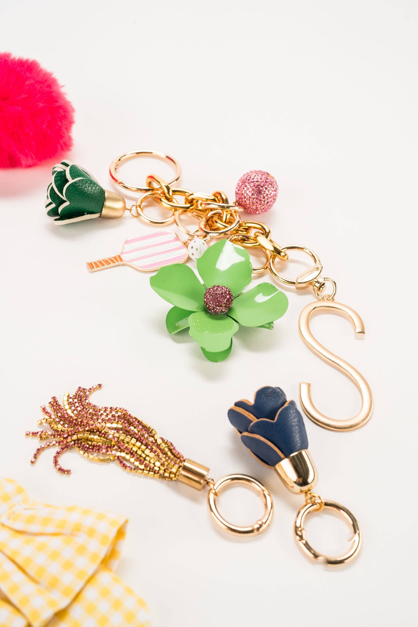 Colorful Leather Flower Tassel keychain with gold "S," pink pom-pom, beaded tassel, and gold rings. Sizes: small, medium.