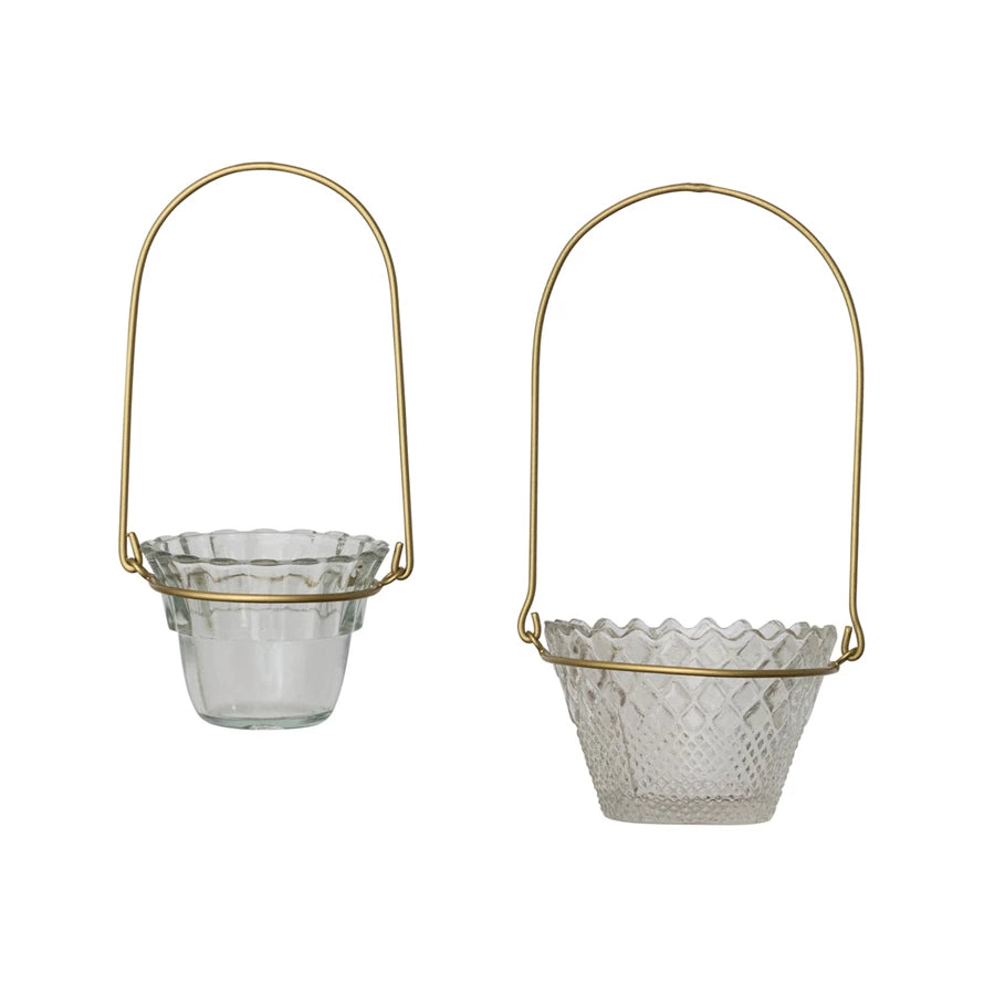 Two pressed glass votive holders with scalloped edges, textured patterns, and antique brass handles. Available in two sizes.