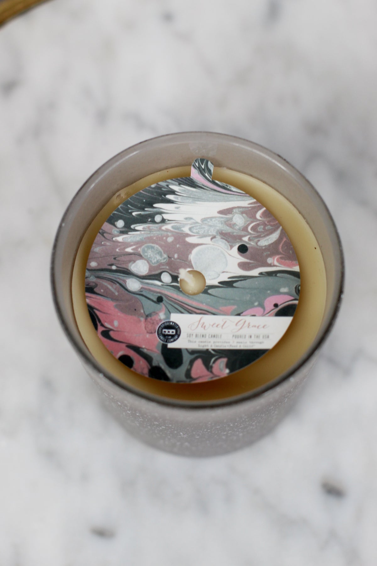Sweet Grace Collection #045 candle in frosted glass with marbled pink, black, and white label. Soy-blend wax. Sizes: S, M, L.