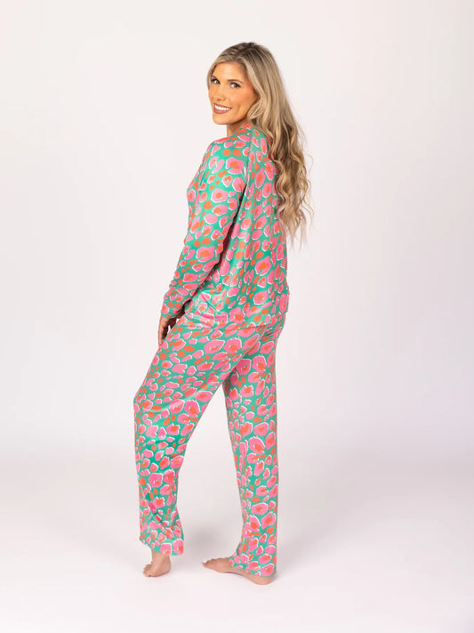 The Wild Child Annie Pajama Set features a vibrant pink and green floral pattern. The set includes a long-sleeved top and matching trousers. Available in sizes small, medium, large, and extra-large.