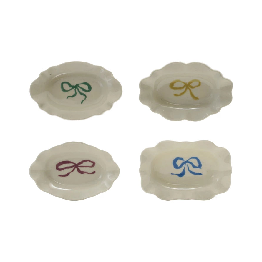 Four white stoneware scalloped dishes with green, yellow, purple, and blue bows. Available in small and medium sizes.