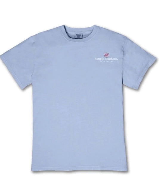 The Walking By Faith Tripping Constantly T-Shirt is light blue with short sleeves, a small “Simply Southern” logo, and a pink turtle graphic on the upper left chest. Available in multiple sizes.