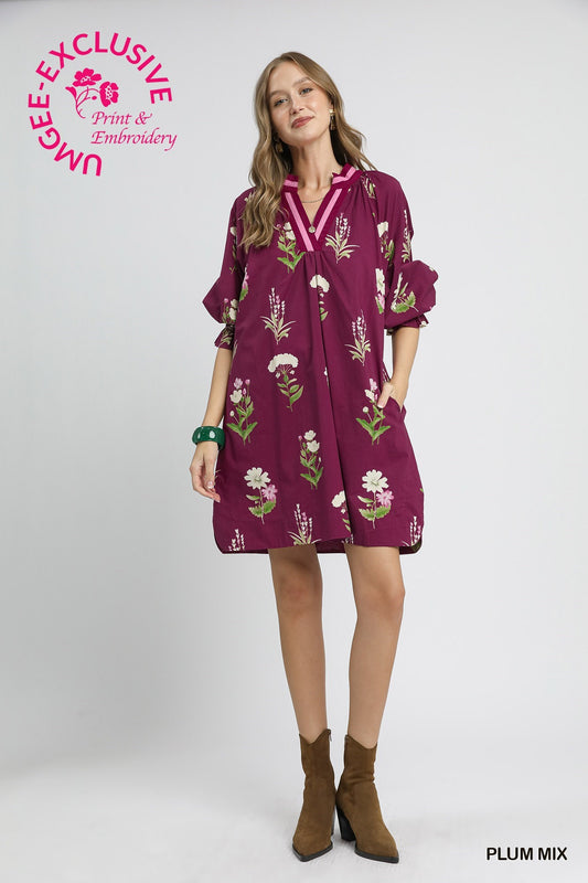 Floral Tunic Dress in plum mix with contrast trim, embroidery, V-neck, rolled sleeves, pockets. Sizes: XS–XL.