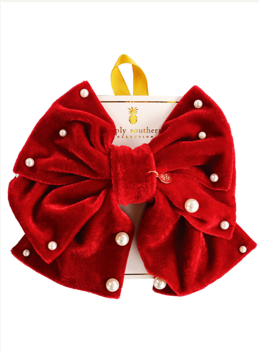 Large red velvet “Bows” accessory with pearl-like beads, on white card with yellow loop; size: large.