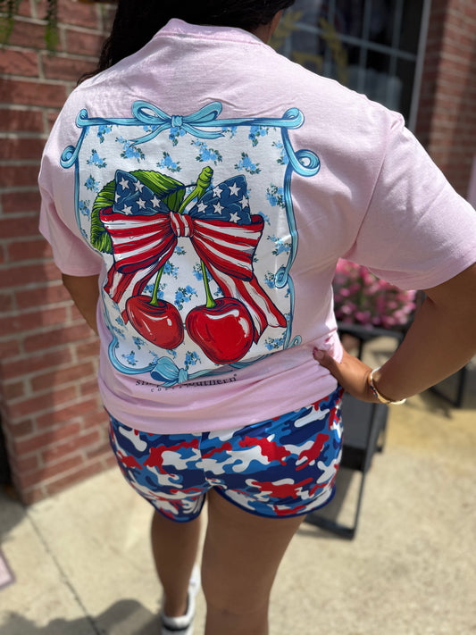 Pink T-shirt with cherry and stars-and-stripes bow graphic on back. Available in sizes XS-XL.