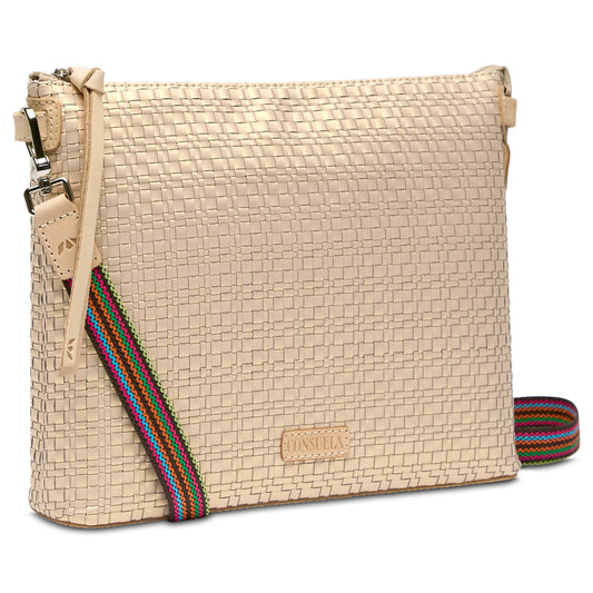 Beige woven crossbody bag with textured exterior, colorful striped adjustable strap, and front leather logo patch. Available sizes: 6" x 9" x 3".