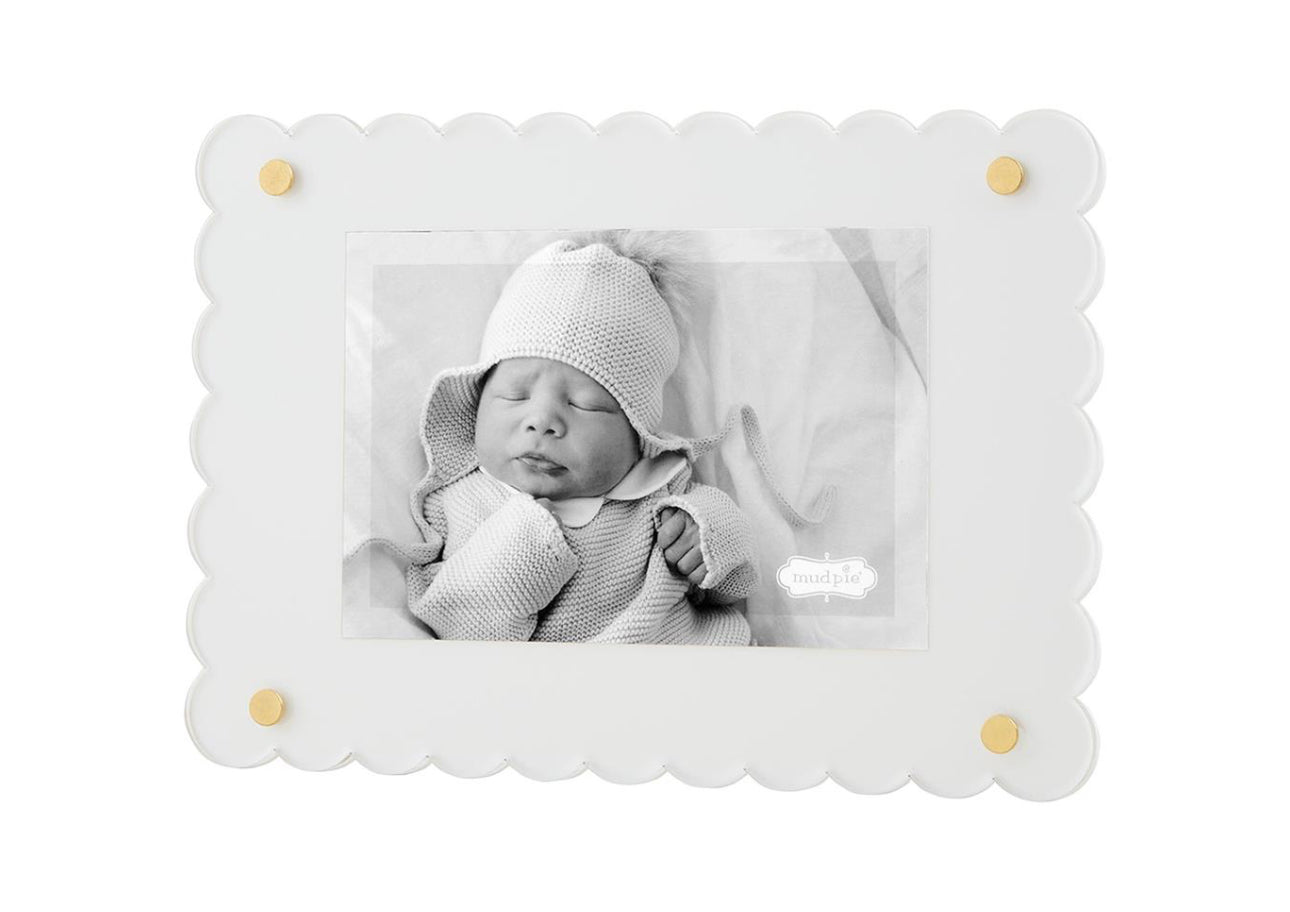 A black and white photo of a newborn wearing a knitted hat and wrapped in a textured blanket, displayed in a Scalloped Acrylic Frame with golden accents.