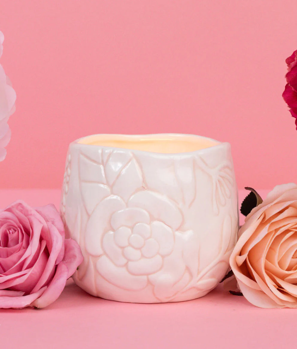 White ceramic candle holder with embossed florals, holding a lit Sweet Grace #57 3 Wick Soy-Blend Candle. Sizes: S, M, L.