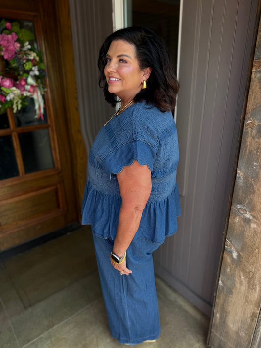Blaire Chambray Smocked Peplum Top with scalloped ruffle sleeves, available in sizes XS–XL.