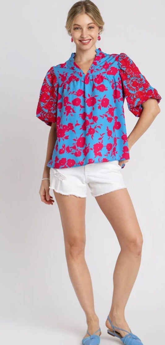 This short puff sleeve top is blue with pink flowers and pink embroidered sleeves . This top comes in small, medium and Large .