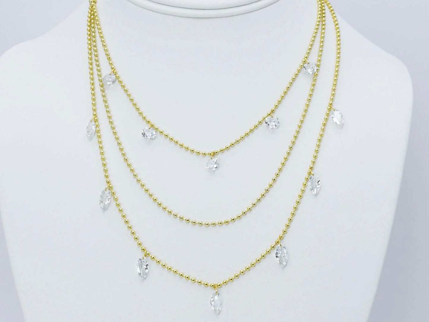 Three gold beaded chains with clear teardrop crystal pendants. Available in 16", 18", and 20" lengths.