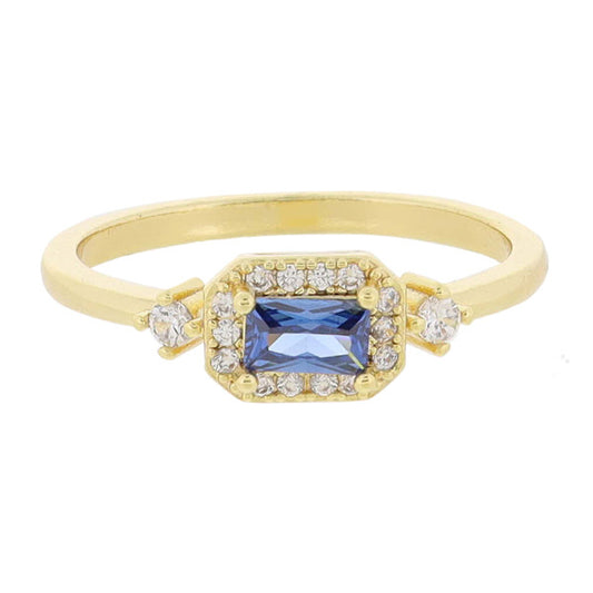 This product is an 18K Gold Plated ring adorned with Mini Crystal Outline and Side Crystals. It boasts a stunning central blue gemstone encircled by smaller diamonds. More diamonds are set on the band for added brilliance. Available sizes for the ring vary.