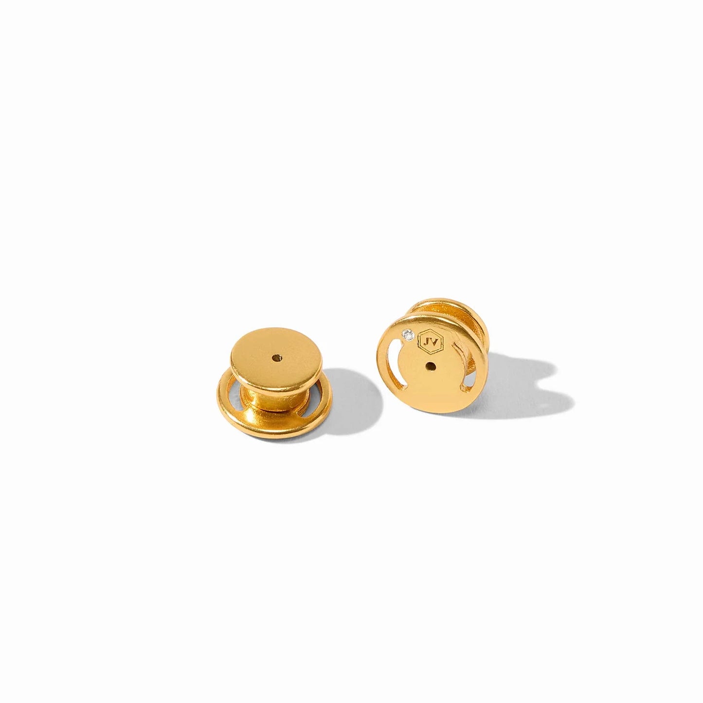 Two small, round, gold-colored Sahara Midi Earrings with flat tops and circular bases, featuring engraved markings and a small gem accent. Available in midi size.