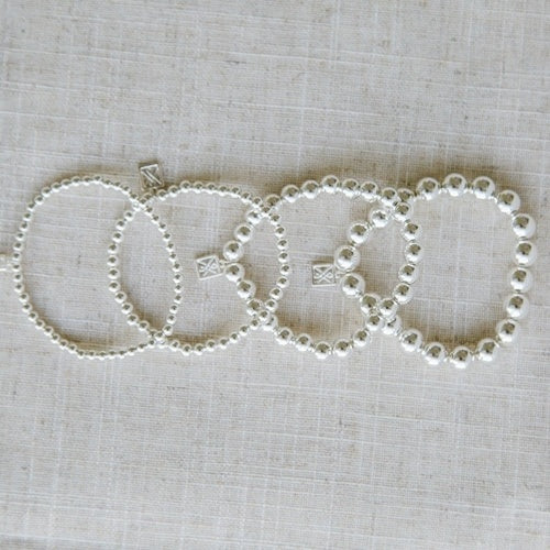 Set of four shiny silver bracelets with varying bead sizes, small square charms. Nickel-free, hypoallergenic. Sizes: S, M, L, XL.