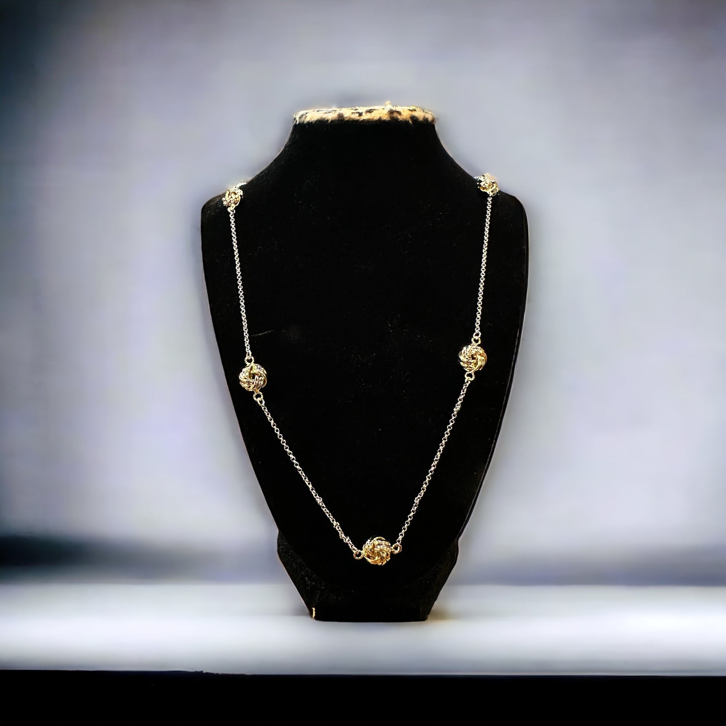 The Knotted Necklace is a long, delicate gold chain with decorative gold beads. Available in 16", 18", and 20" lengths.