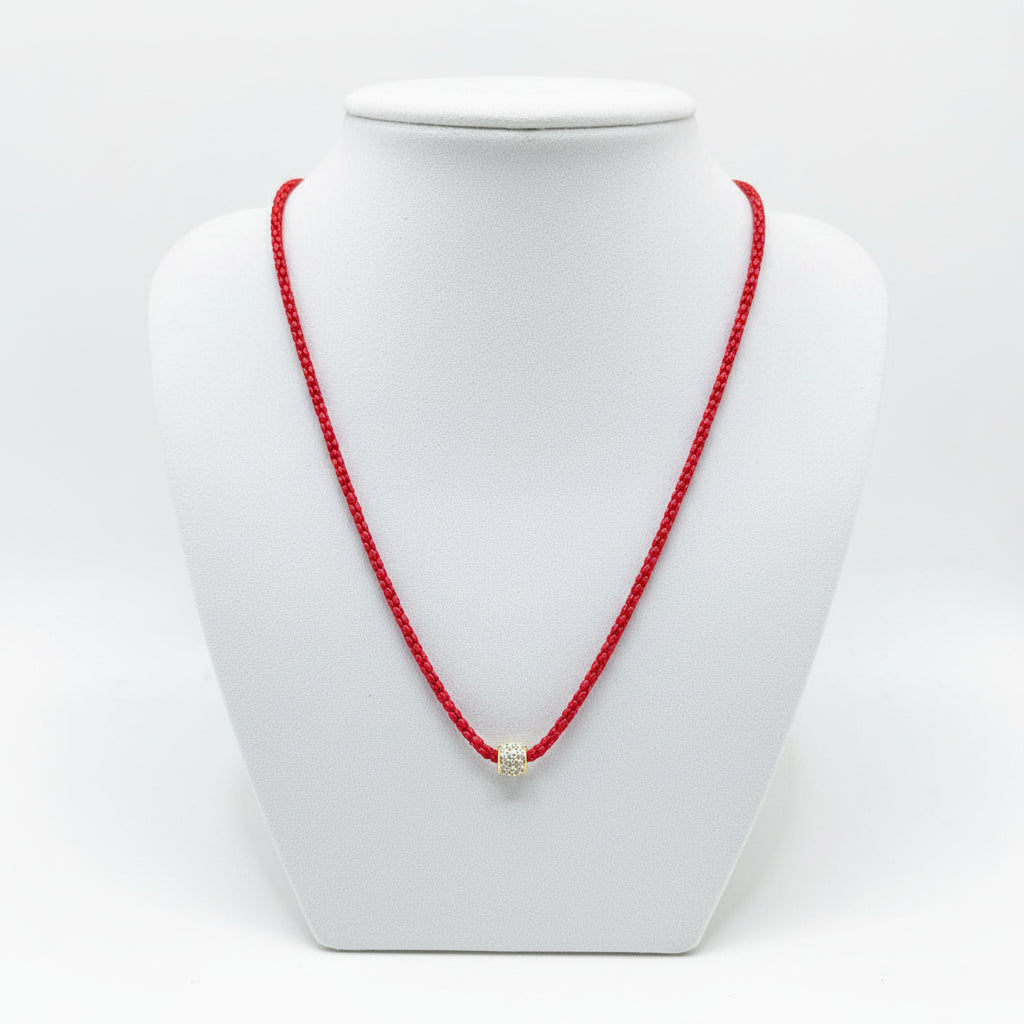 The Cassie Red Necklace has a vibrant red snake chain, a small cylindrical pendant with gold and gem accents. Available in multiple sizes.