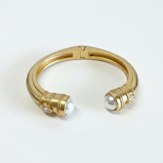 Gold-dipped stainless steel cuff with rounded ends, each set with a large white pearl and small diamonds. Sizes: S, M, L.