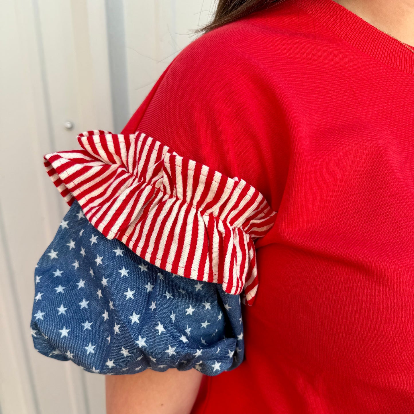 Liberty Ruffle Accent Puff Sleeve Top with red/white stripes, blue/white stars. Available in sizes XS-XL.