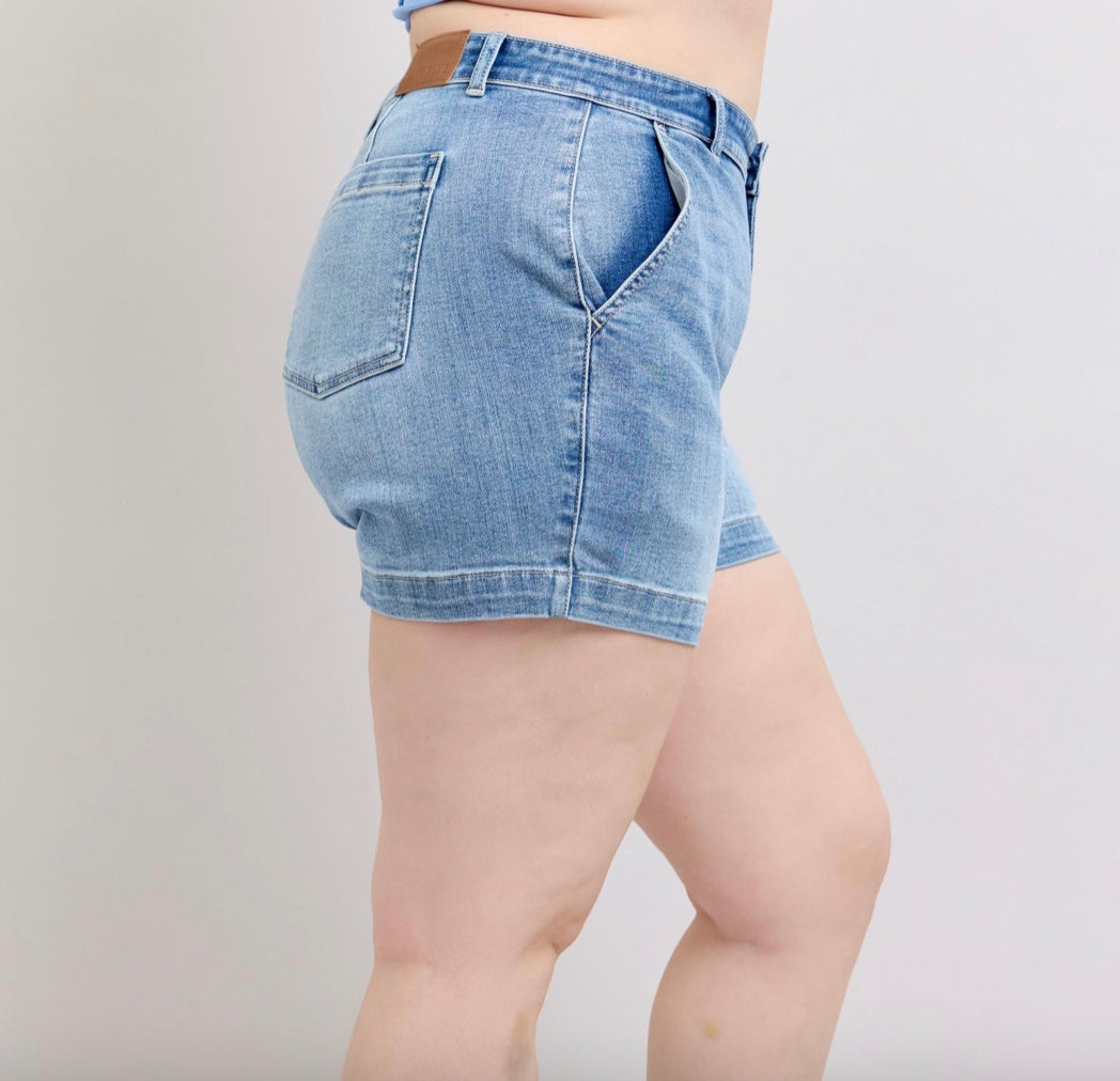 Judy Blue Mid Rise Trouser Shorts are light blue denim shorts with pockets. Available sizes: S, M, L, XL.