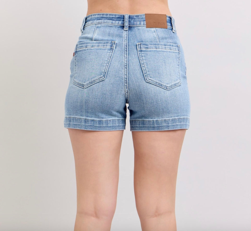 Light blue denim shorts with rolled hems, two back pockets, and a brown leather patch on the waistband. Available in sizes S, M, L, XL.