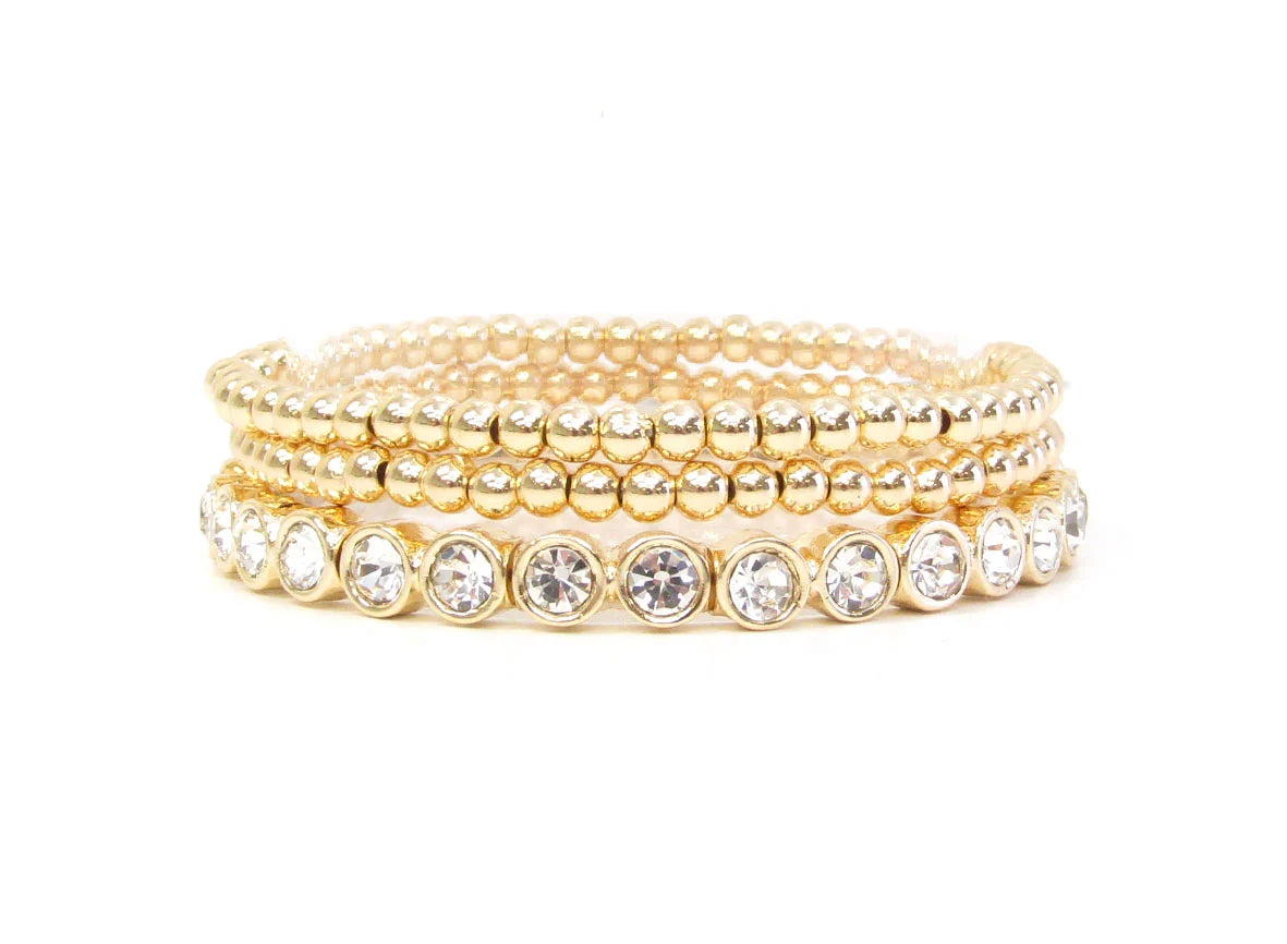 Logan Multi Strand Diamond Stretch Bracelet Stack: Four gold beaded bracelets, including one with clear round gemstones in bezel settings. Available sizes: S, M, L.