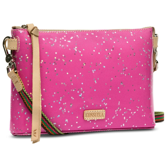 Consuela Midtown Crossbody in Berry with bright pink glitter, silver star patterns, tan leather accents, and multicolored adjustable strap. Available sizes: small, medium.