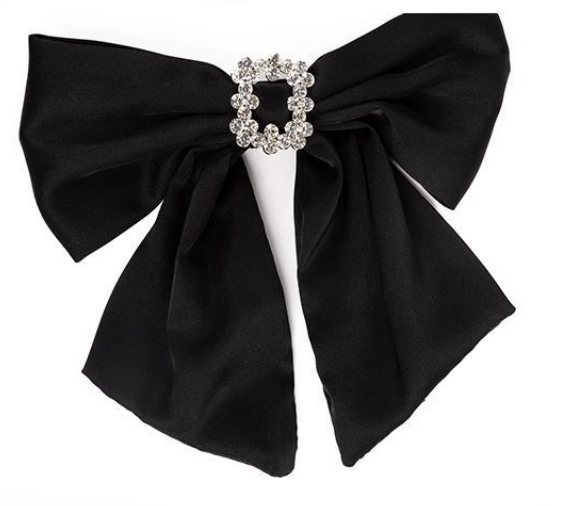 The Holiday Bows: Black satin-like bow with a silver-colored brooch encrusted with small, sparkling gems. Features two long tails. Sizes: N/A.
