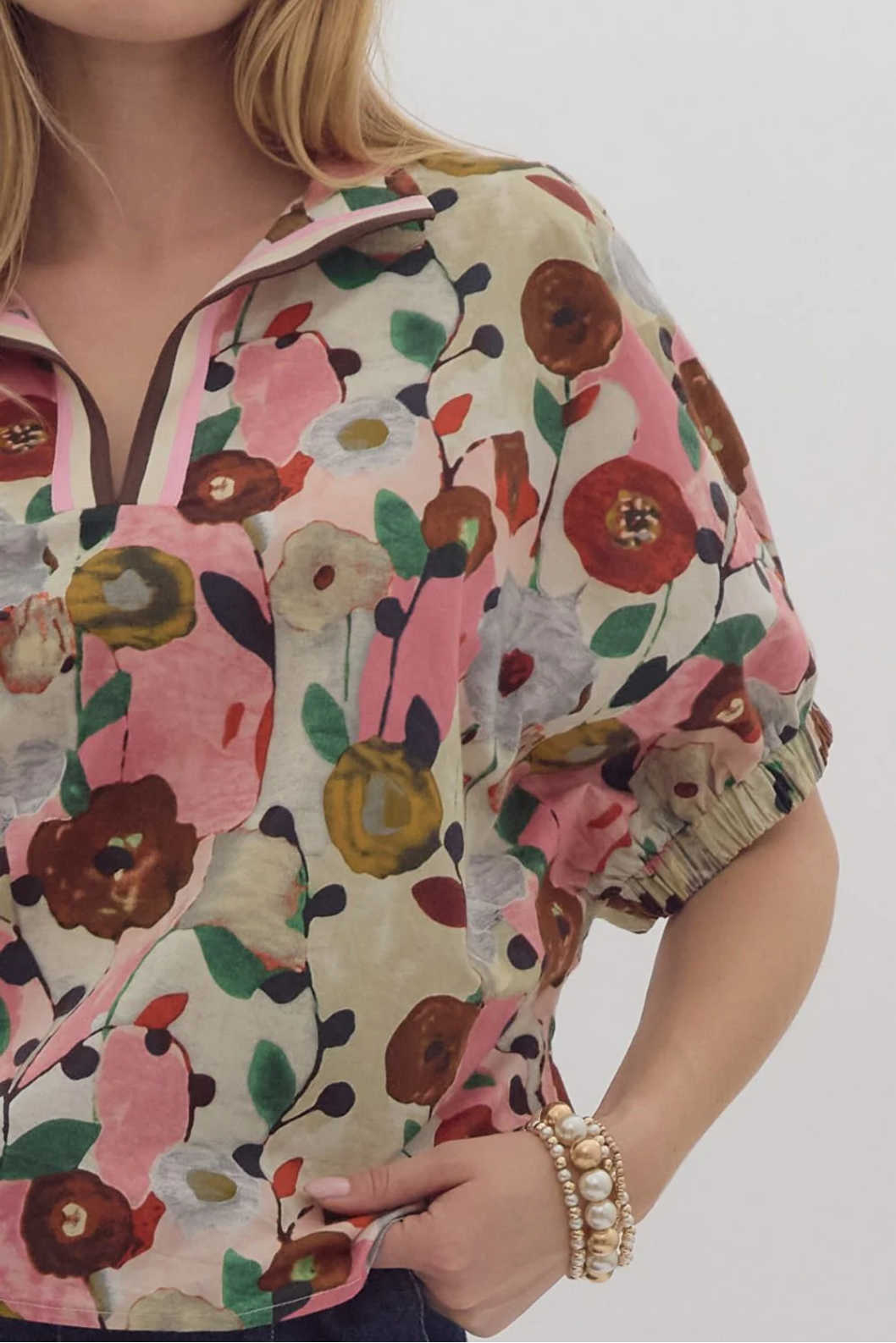 The Flora Top features a vibrant floral-patterned v-neck and puffed sleeves. Available in sizes XS, S, M, L, and XL.