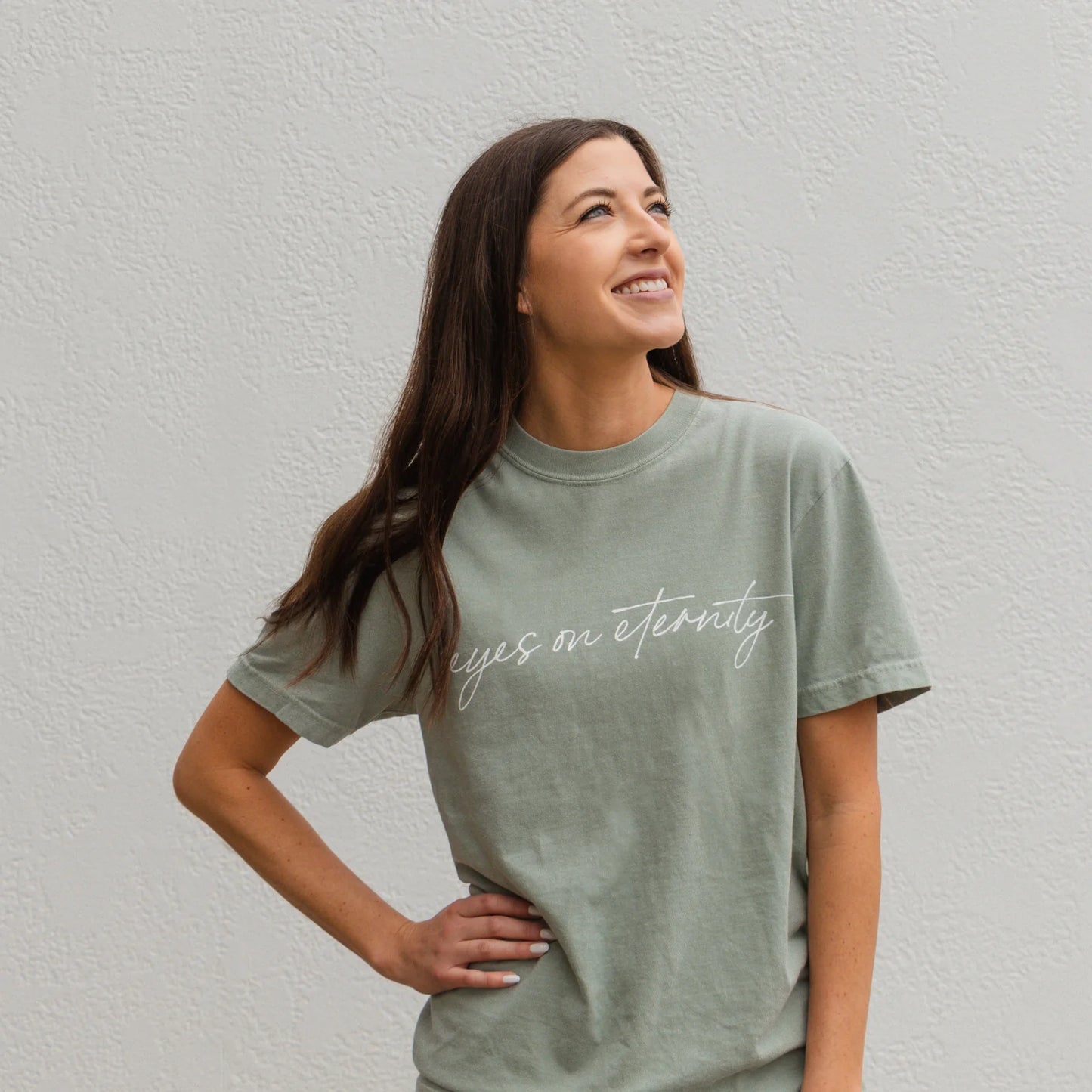 Sage green Eyes on Eternity Tee with "eyes on eternity" in cursive. Available in sizes S-XXL.