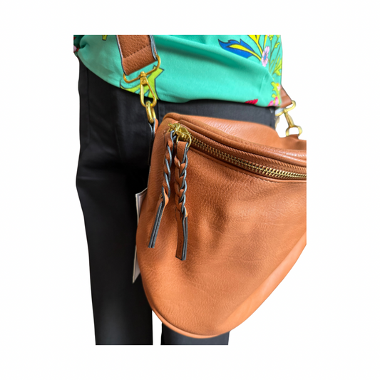 Megan Sling Bag in tan vegan leather with adjustable strap, gold zipper, and braided pull. Sizes: S, M, L.