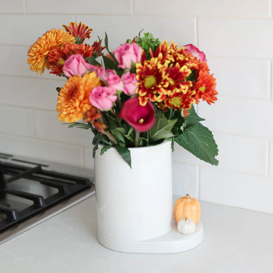 White ceramic Pinstripes Utensil Crock, available in multiple sizes, features a bouquet of orange, yellow, and pink flowers.