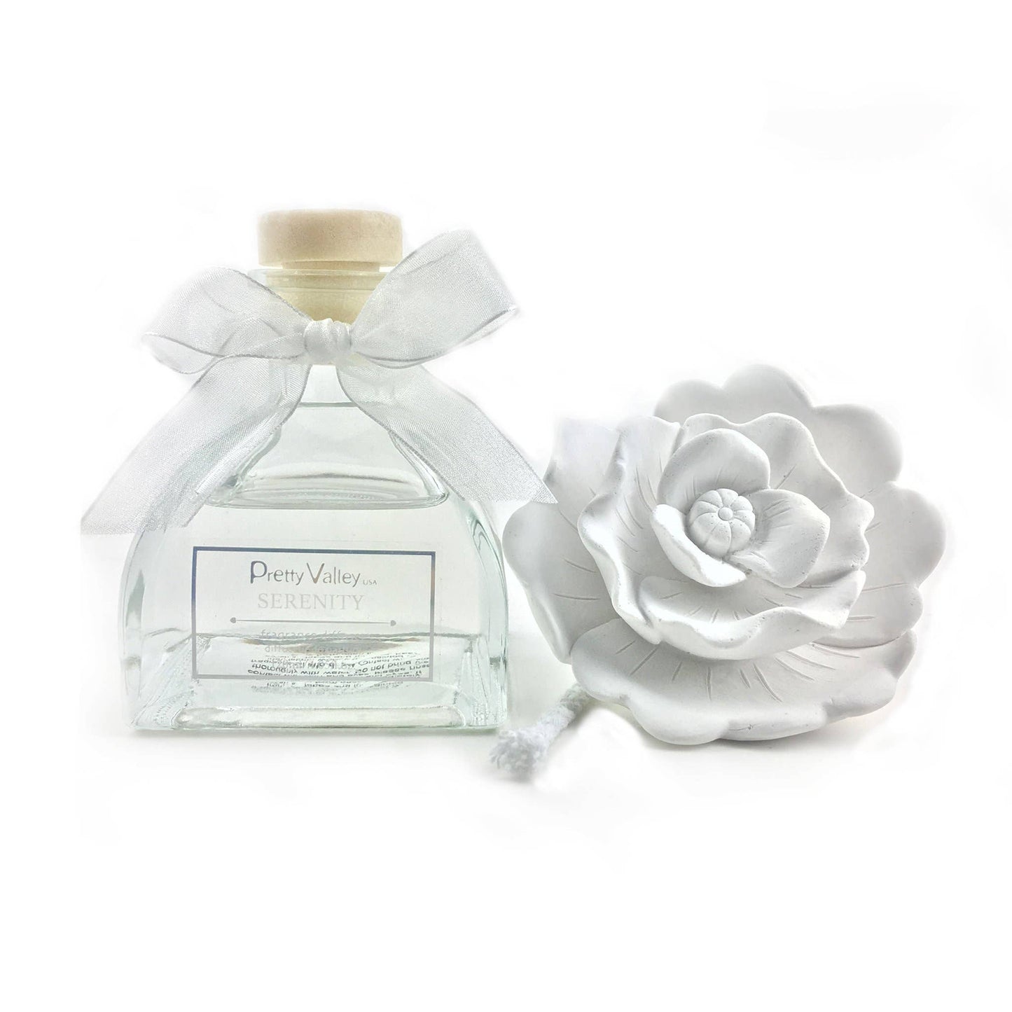 Clear glass bottle with wooden cap, white ribbon, and sculpted ceramic flower diffuser; sizes available: 100ml, 200ml.