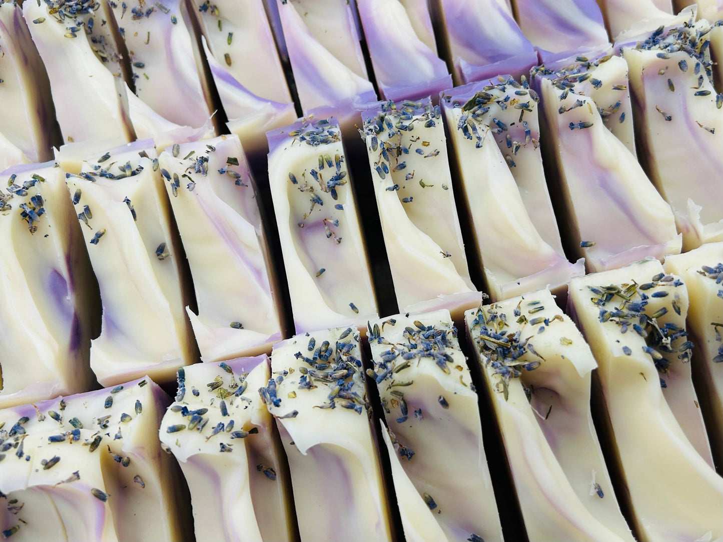 This Rows of Lavender Handmade Soap Bars are crispy and aromatic, enhanced with tiny sprinkles of dried lavender buds. The soap is marked by intriguing swirls of white and purple colors, offering aesthetic appeal along with its inherent functions. No size options available as this product comes in a standard singular size.