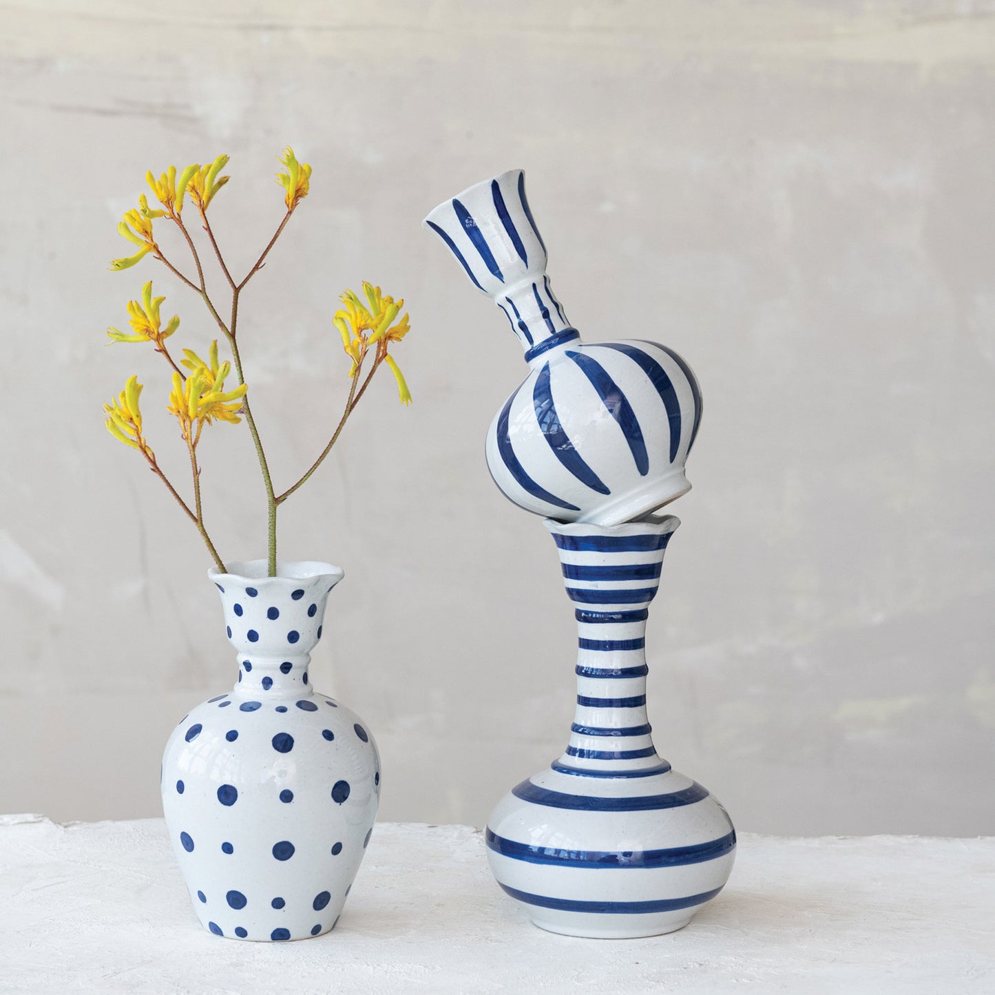 Ceramic vases from the Hand-Painted Stoneware collection, featuring a blue polka-dot design with yellow flowers and a striped blue and white pattern. Sizes: 9"H, 10"H.