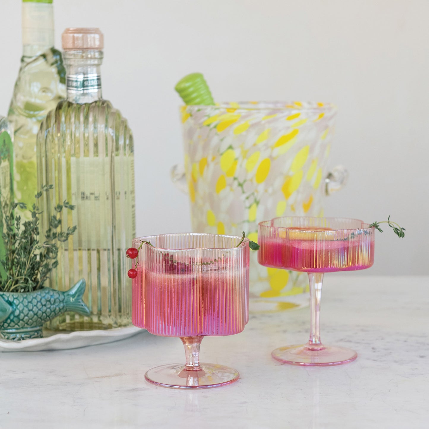 Two pink hand-blown pleated flower-shaped stemmed wine glasses with iridescent finish. Sizes: Standard.