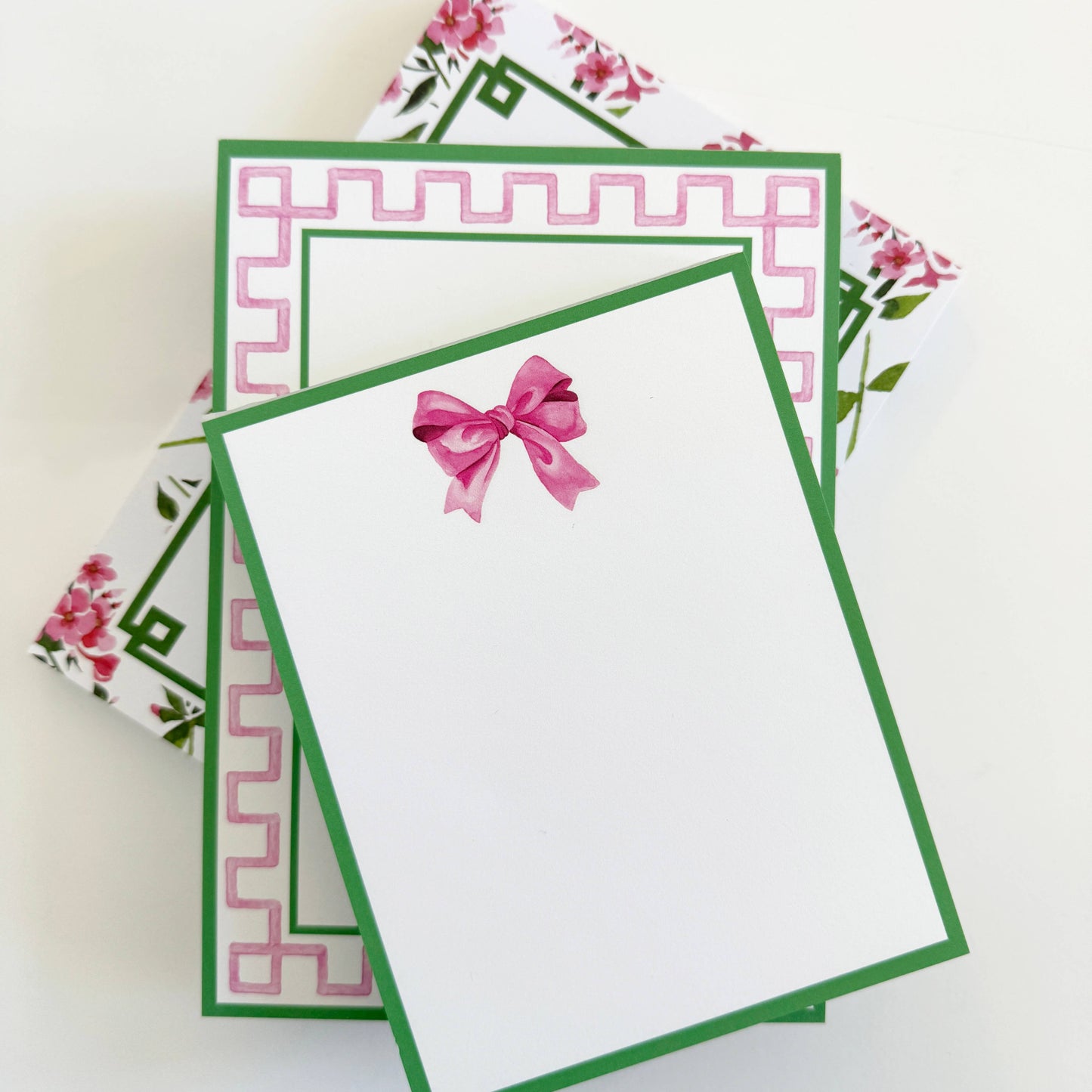 4.25 x 5.5 Pink Bow Notepad with green borders, pink geometric pattern, floral accents, and a pink bow illustration at the top.