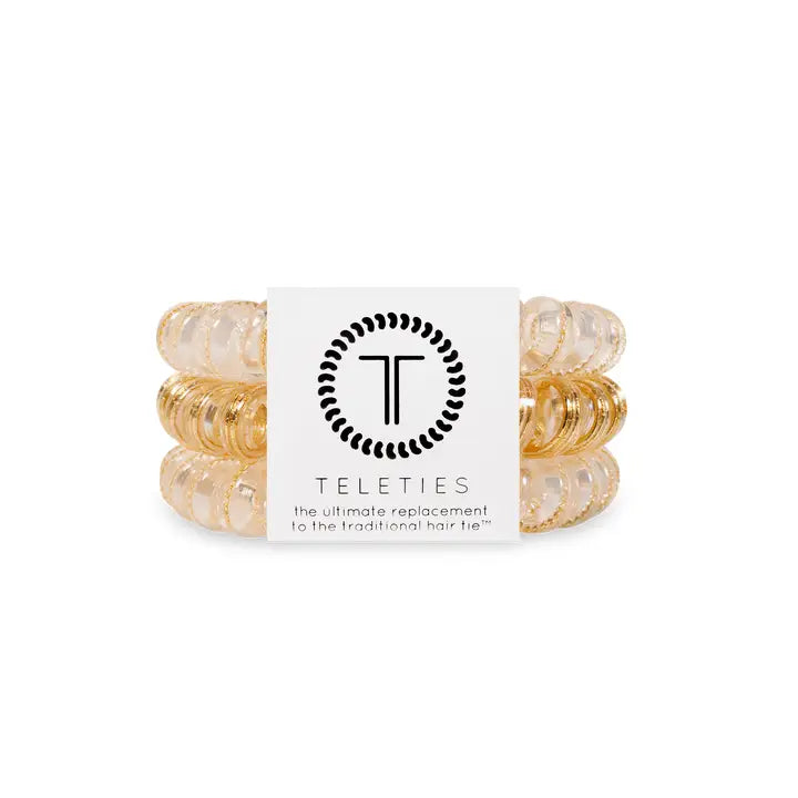 Three clear and gold coiled TELETIES Hair Ties with a white "TELETIES" label. Available in small, medium, and large sizes.