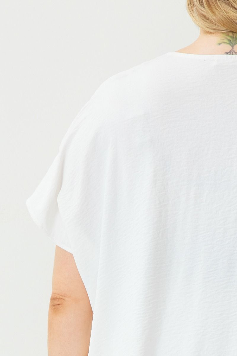 Solid maroon V-neck top featuring short sleeves. The material showcases intricate fabric details. Available in sizes S, M, L, and XL.