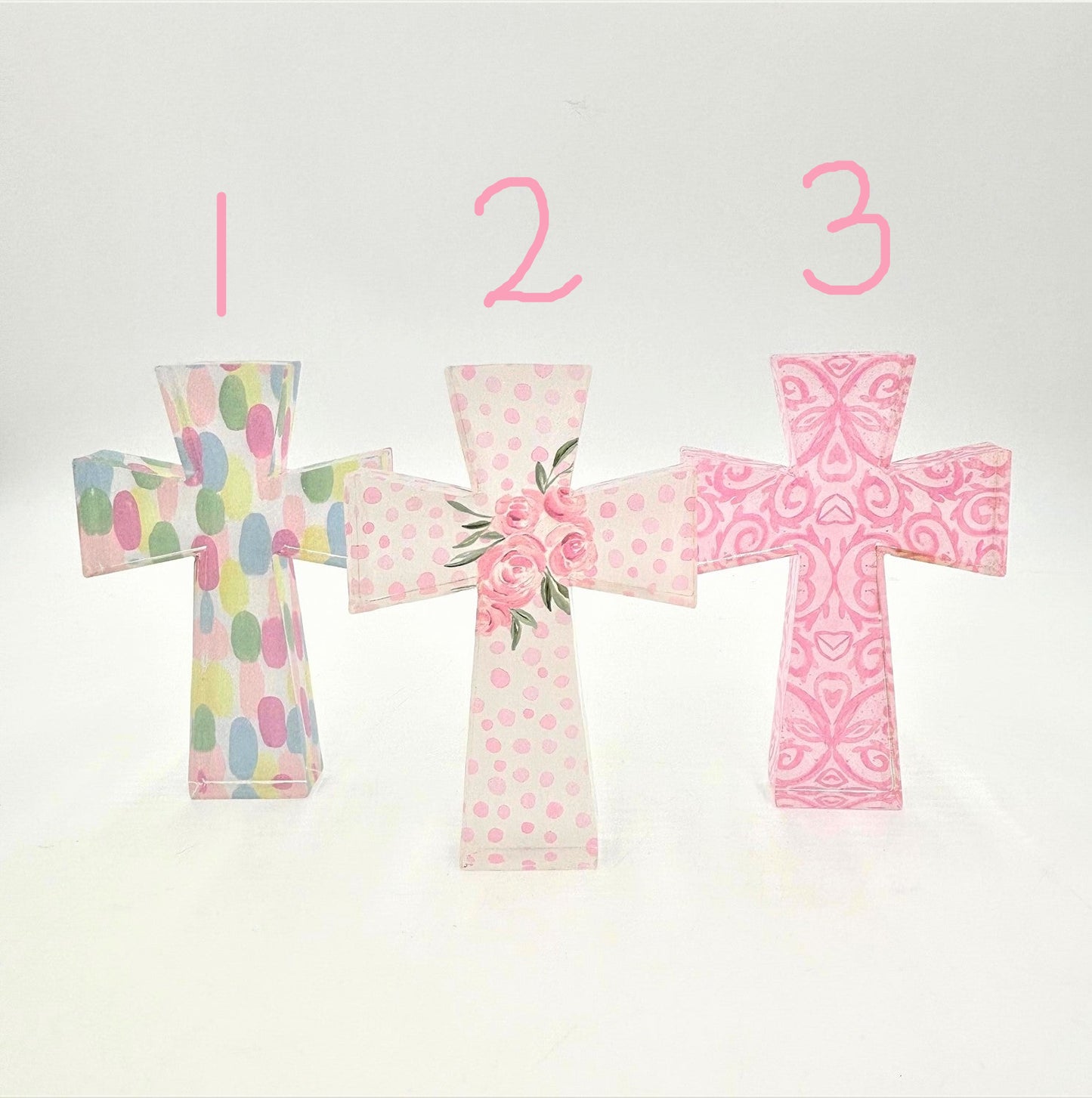 The Pastel Cutout Acrylic Crosses feature three designs: Cross 1 with pastel polka dots, Cross 2 with pink roses on a pink polka dot background, and Cross 3 with a vibrant pink paisley design on white. Sizes available: Small, Medium, Large.