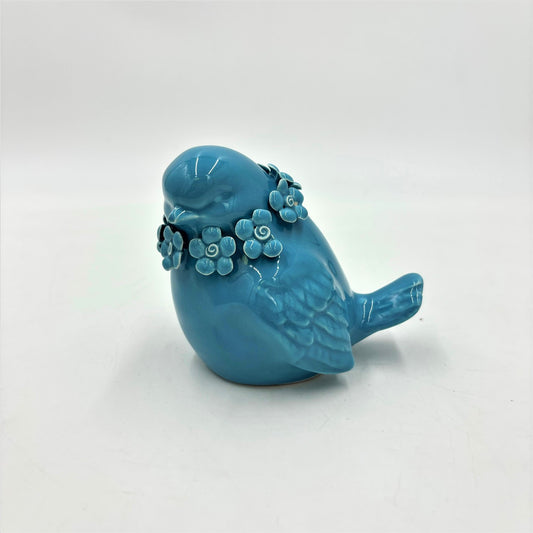 Ceramic bird figurine with a floral wreath, measuring 3x3.5x4 inches. Available in a blue finish with a white surface base.